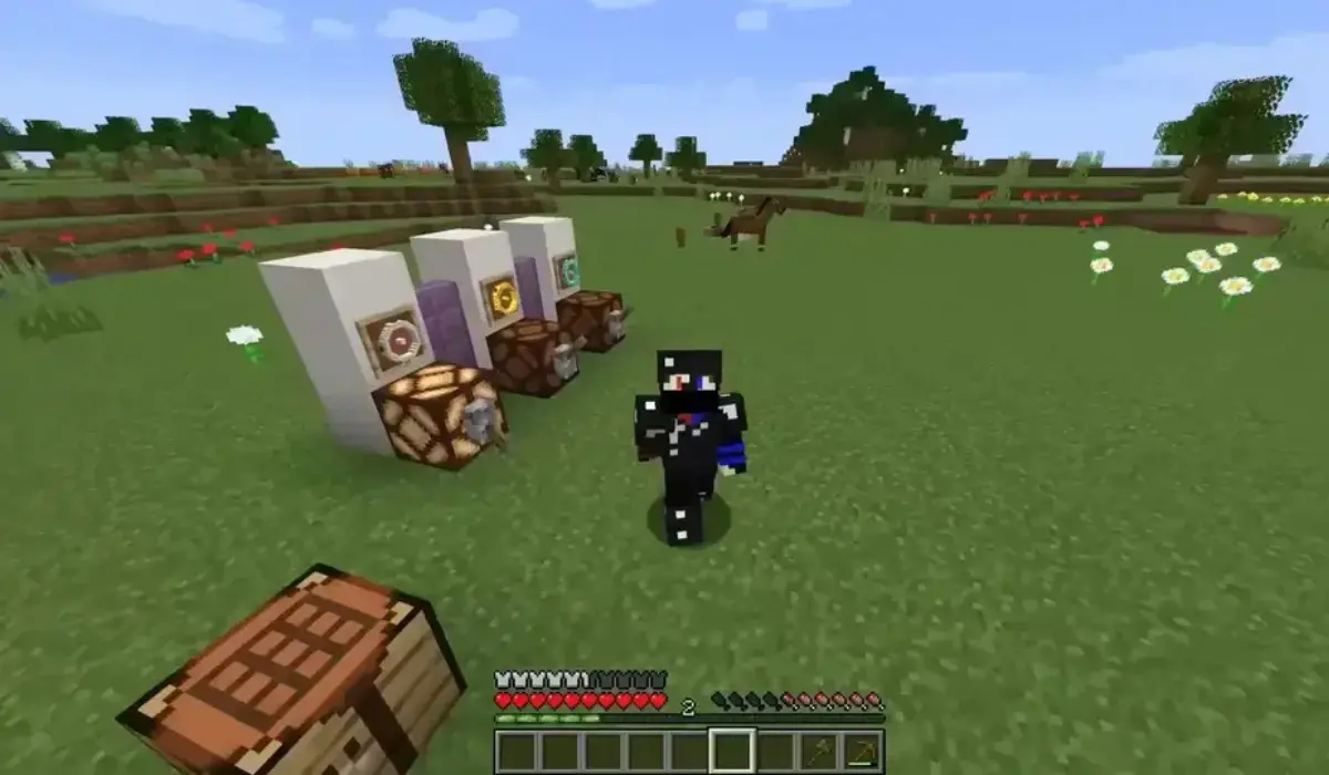 A Minecraft player in black armor stands on grass near crafting tables and redstone contraptions with item frames; trees and animals are visible in the background, showcasing features from the Minecraft latest version.